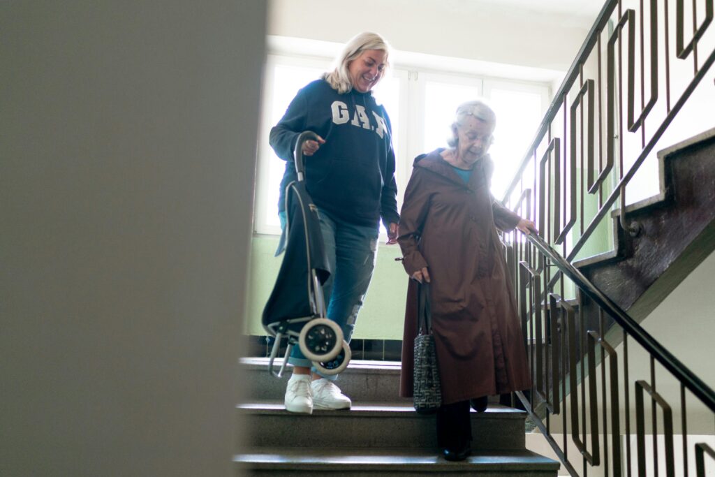 Elderly Caregiver Assisting Senior Down Stairs
